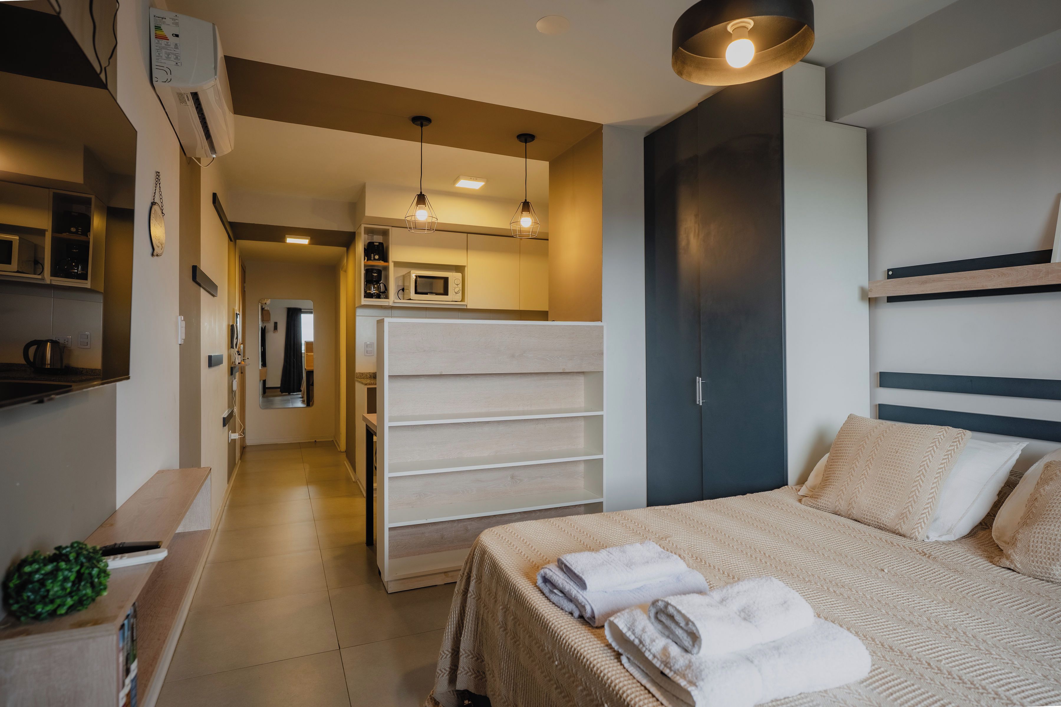 Una habitación de hotel con cama, armario, espejo, microondas y cafetera.