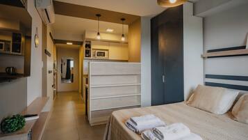 Una habitación de hotel con cama, armario, espejo, microondas y cafetera.