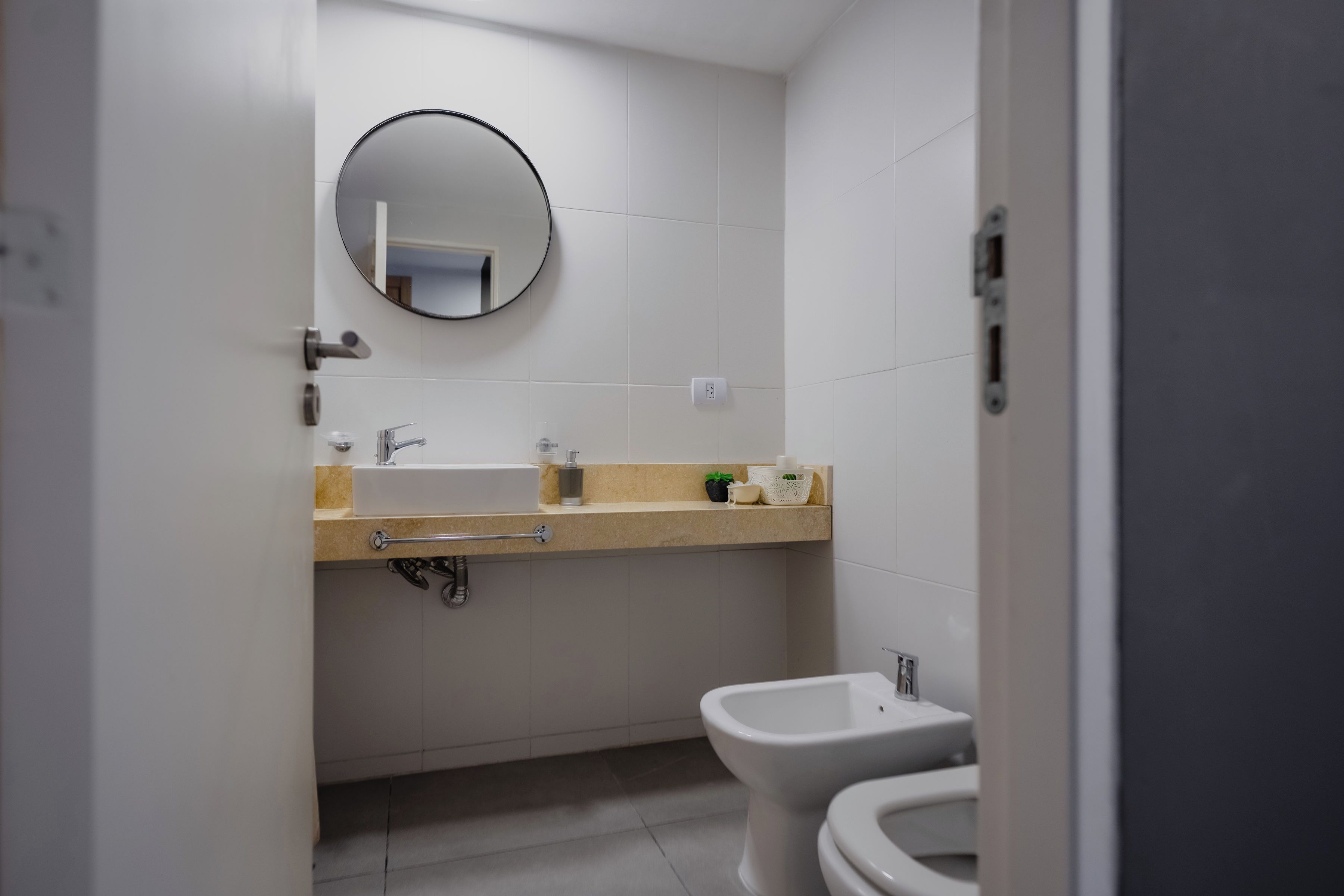 Un baño con inodoro, lavamanos, espejo y toallero.