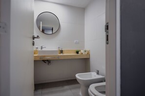 Un baño con inodoro, lavamanos, espejo y toallero.