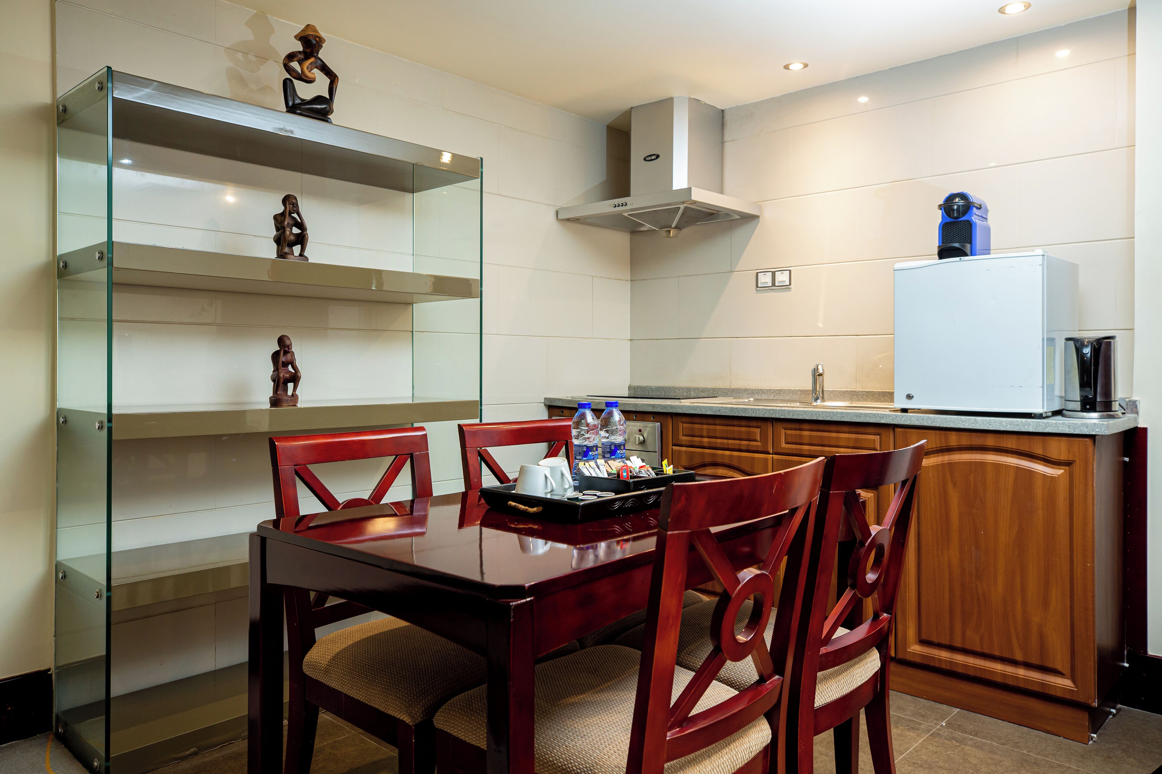 Une cuisine moderne avec des meubles en bois, une étagère en verre et une table à manger avec des chaises.