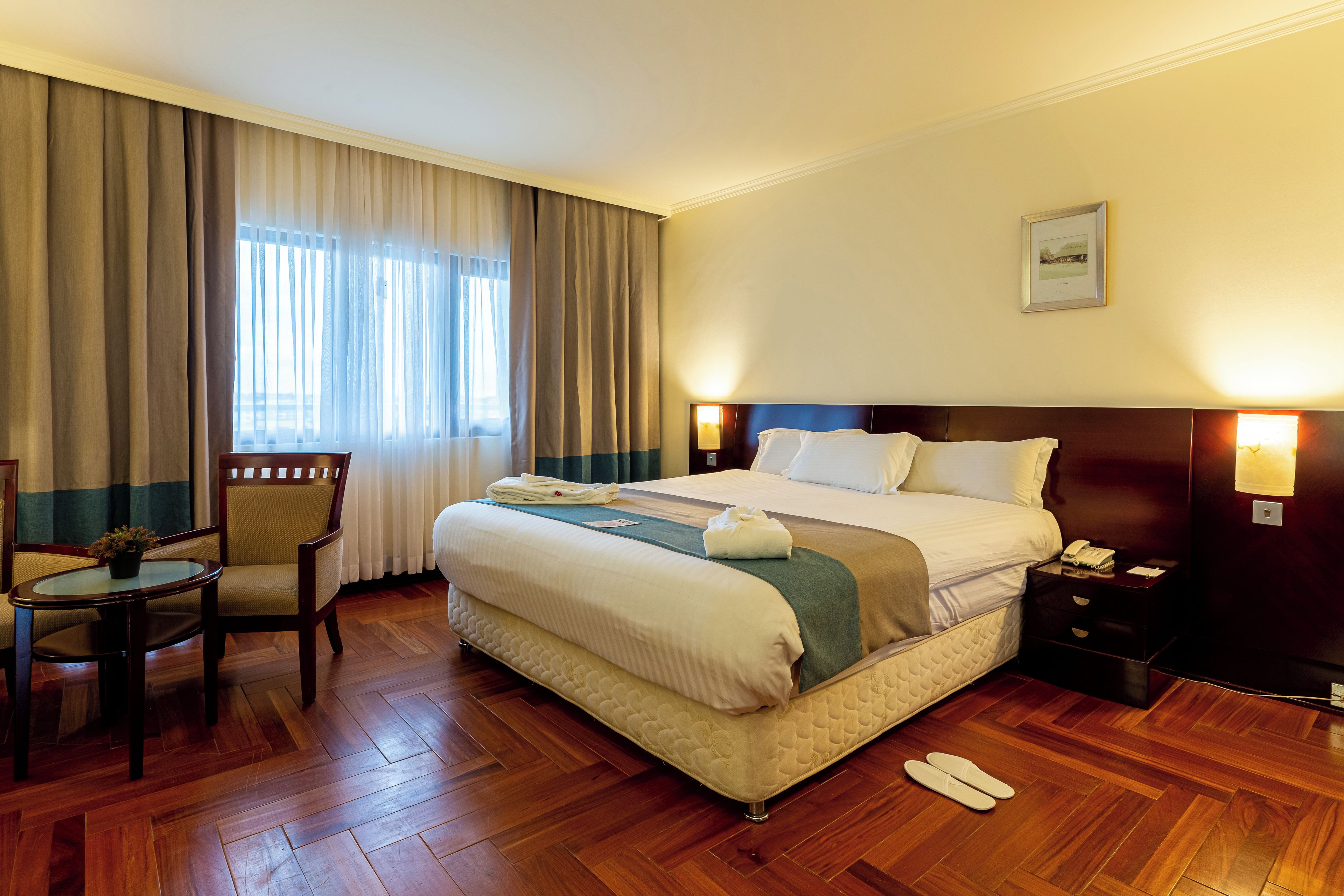 Une chambre d’hôtel avec un grand lit, une chaise, une table et une table de chevet.