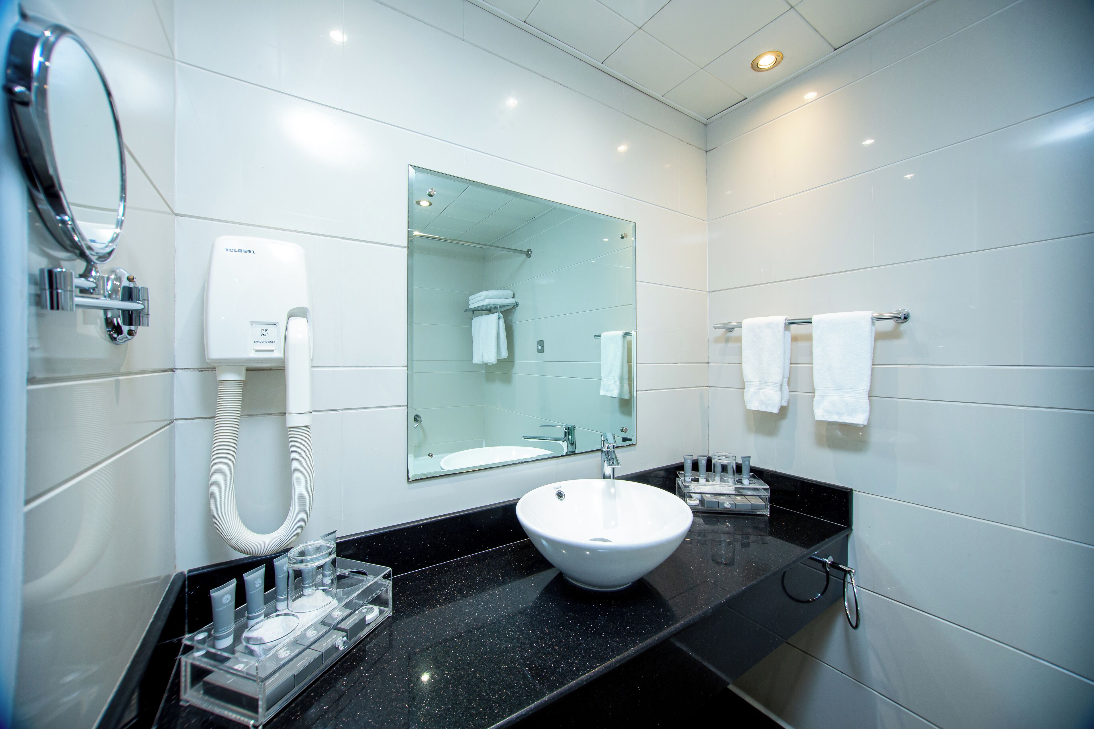 A modern bathroom with a white sink, a glass-enclosed shower, and a mirror above the sink.