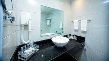 Une salle de bain moderne avec un lavabo blanc, une douche à parois de verre et un miroir au-dessus du lavabo.