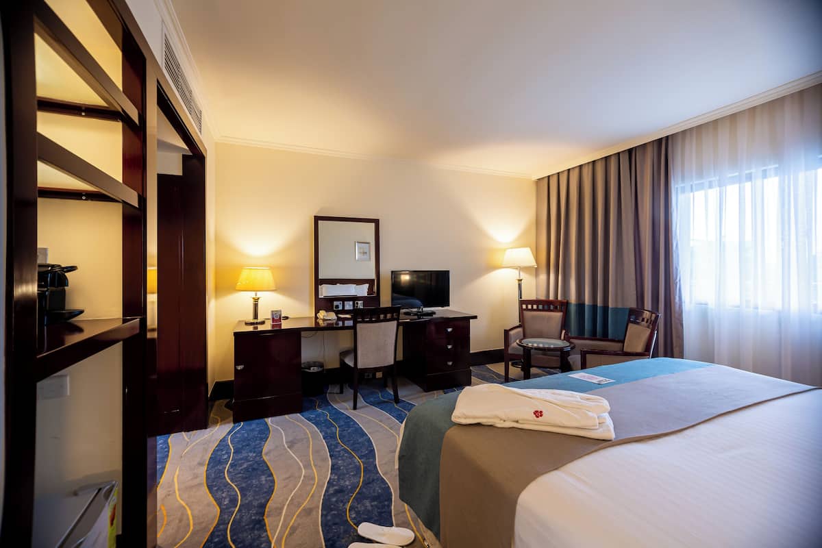 A hotel room with a bed, desk, chair, and a television.