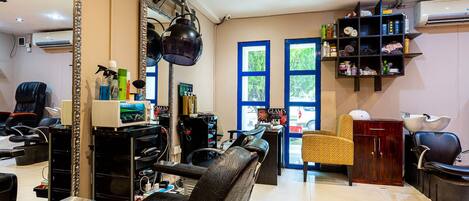 A salon with a large mirror, black leather chairs, shelves with hair products, and a view of the outside through a window.