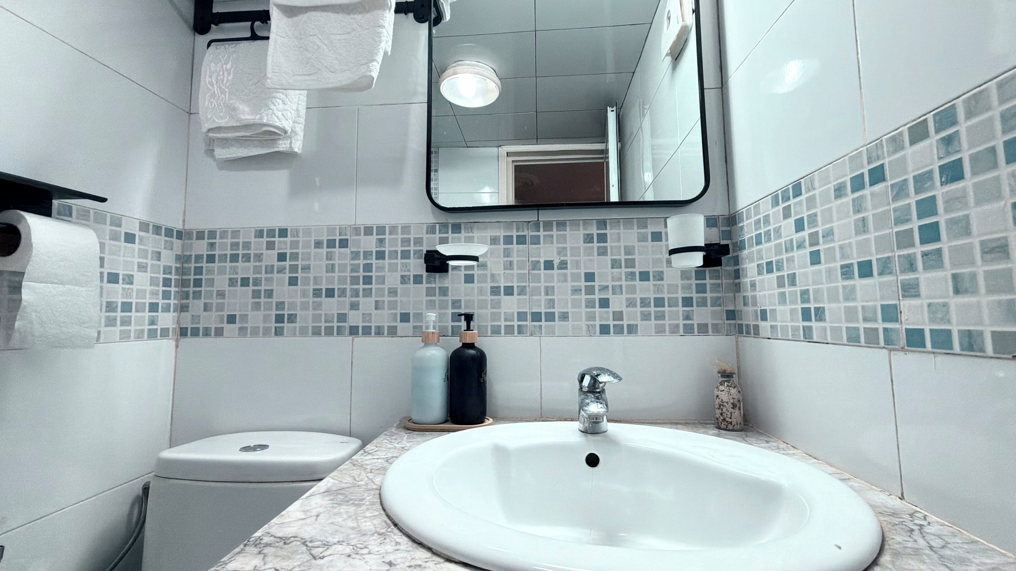 A bathroom with a white sink, a toilet, and a mirror.