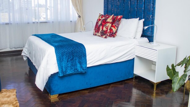Une chambre à coucher moderne avec un grand lit, une table de chevet blanche et une tête de lit bleue.