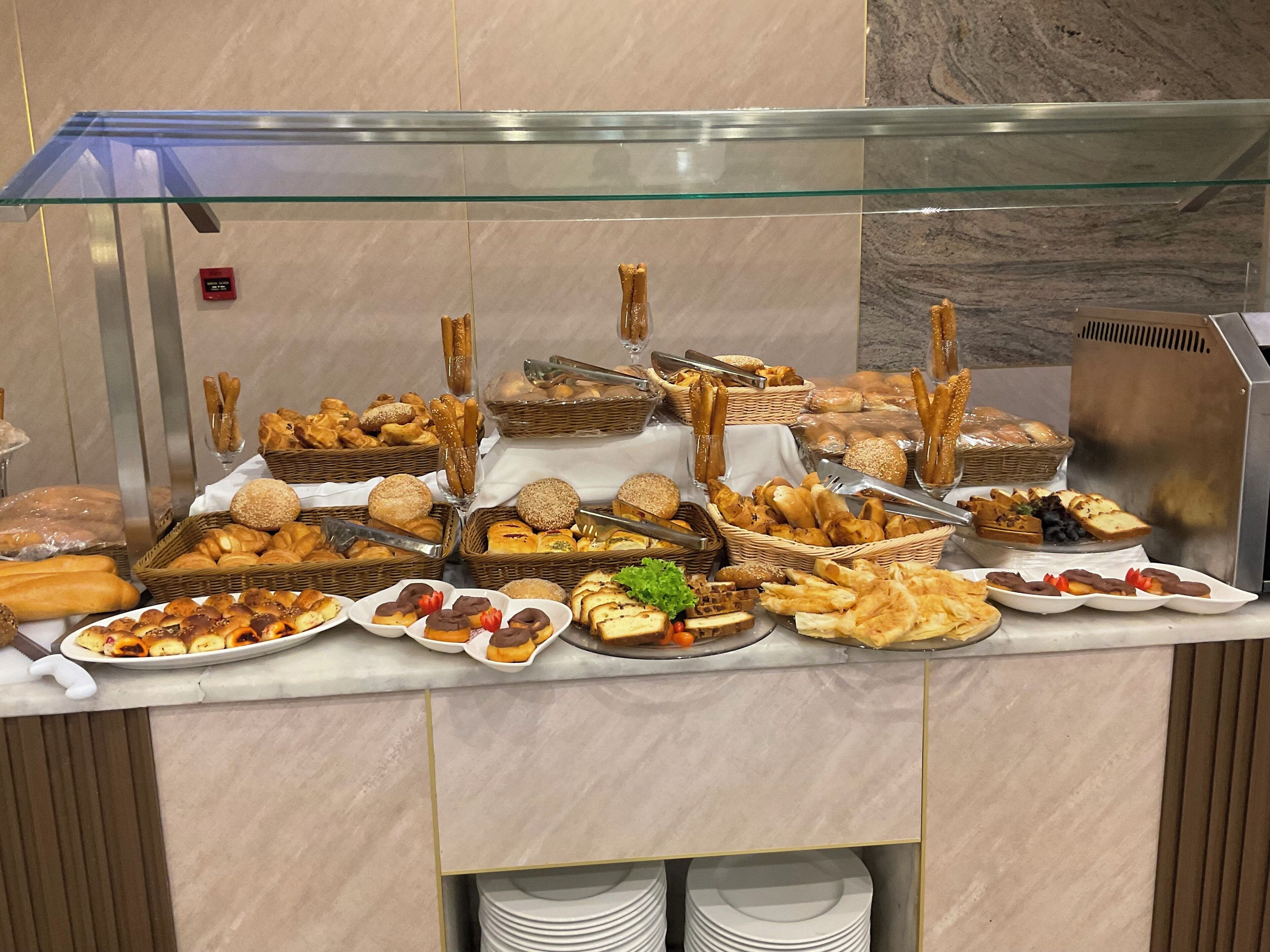 A buffet with various baked goods and pastries displayed in baskets and plates.