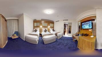A hotel room with two beds, a desk, a TV, and a bathroom.