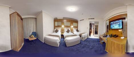 A hotel room with two beds, a desk, a TV, and a bathroom.