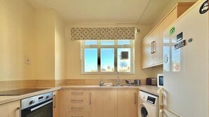 A compact kitchen with a built-in oven, a washing machine, and a refrigerator. - Spacious Flat in Nine Elms (London)