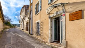 Una calle estrecha flanqueada por edificios, un letrero y una puerta con ventanal.