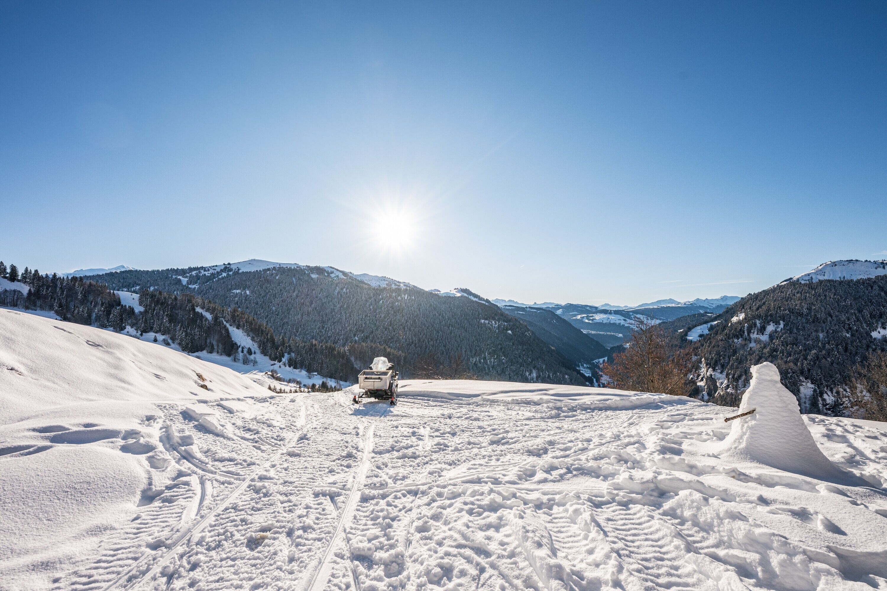 Paisagem montanhosa coberta de neve com um veículo e um boneco de neve.