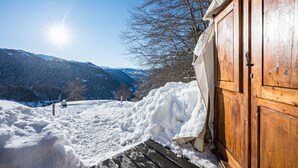 Une cabane en bois offrant une vue sur des montagnes enneigées et un ciel dégagé.