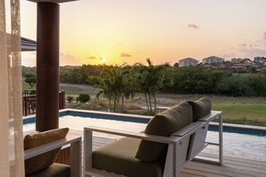 Zona de piscina con vistas a la puesta de sol, una piscina y una hilera de edificios al fondo.