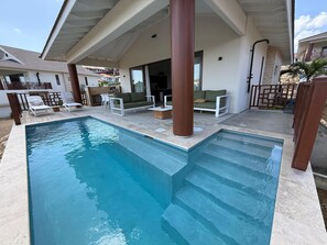 A swimming pool with steps leading into it, surrounded by outdoor furniture and a covered patio area. - Villa Jazmyn 6 Blue Bay Resort, pool, beach @300m, front row Golf Course (Willemstad)