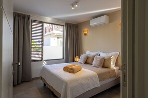 A bedroom with a bed, curtains, an air conditioning unit, and a window with blinds. - Villa Jazmyn 6 Blue Bay Resort, pool, beach @300m, front row Golf Course (Willemstad)