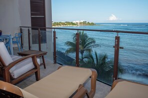 Ein Balkon mit zwei Loungestühlen, einem kleinen Tisch und Blick auf das Meer und den Strand.
