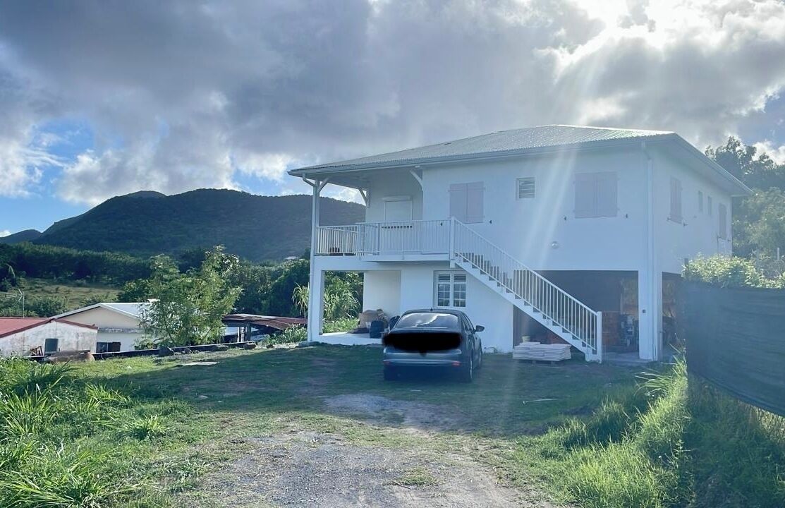 A two-story house with a car parked in the driveway.