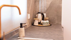 A modern kitchen with a marble backsplash, stainless steel appliances, and a wooden faucet. - AMELI COZY APARTMENTS  (Spata-Artemida)