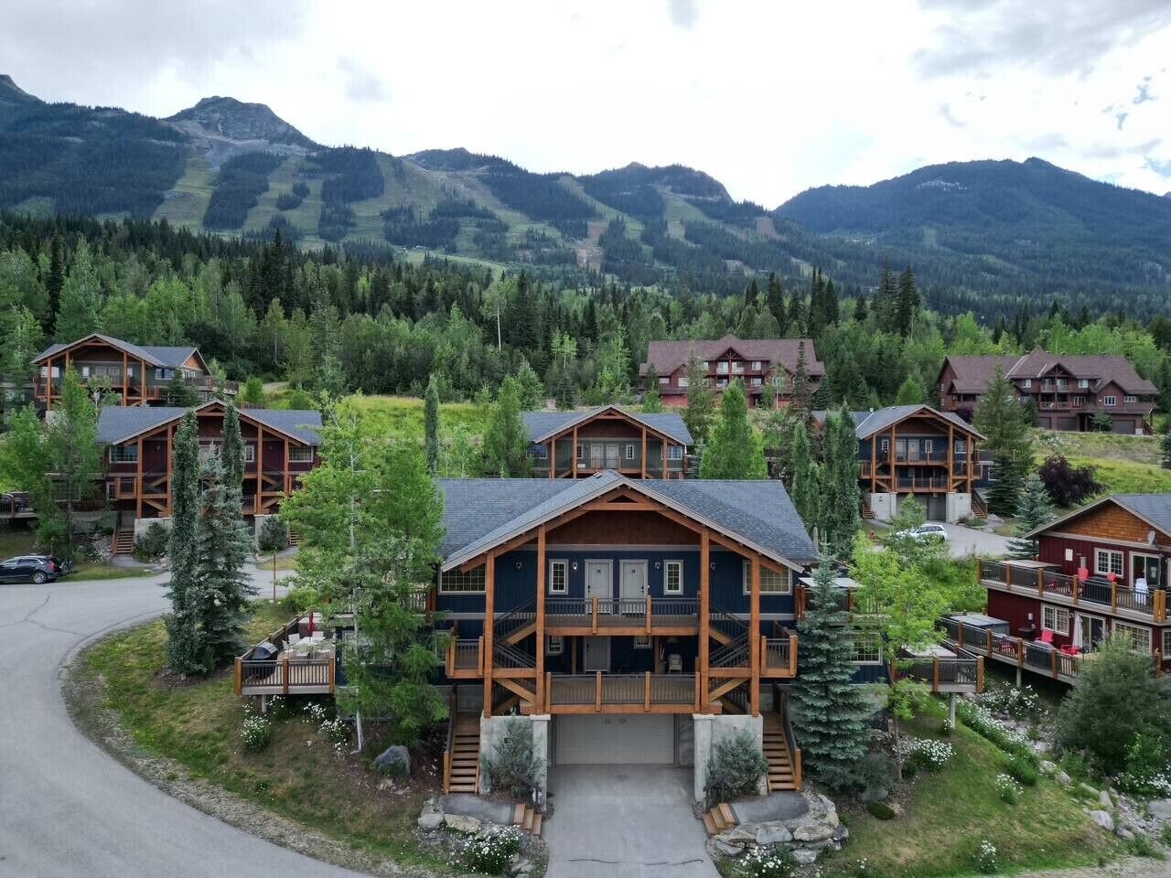 A lodge with multiple wooden cabins, a central building with a porch, and a mountainous backdrop.