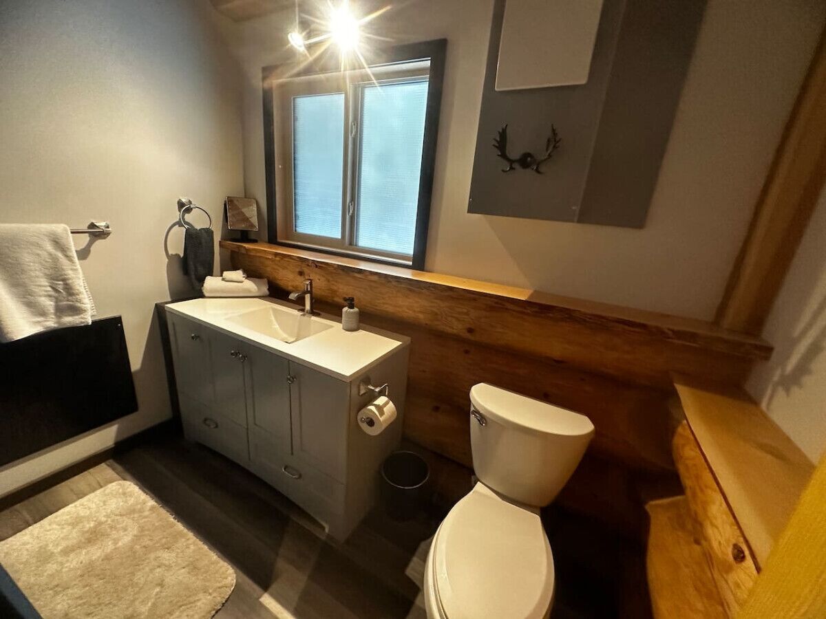A bathroom with a toilet, sink, and window.