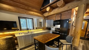 Une cuisine moderne avec des poutres en bois, un grand îlot central et un coin bar.