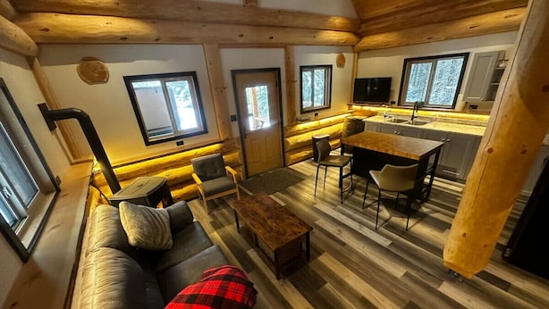 Un intérieur de chalet chaleureux avec un canapé, des fauteuils, une table basse et un coin repas.