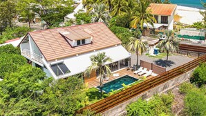 Una propiedad costera con piscina, terraza de madera y vista al océano.