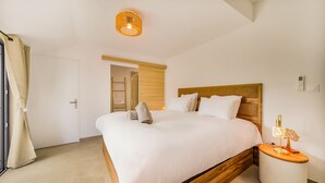 Una habitación de hotel moderna con una cama grande, cabecera de madera y una mesita de noche con lámpara.