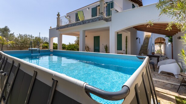 Ein zweigeschossiges Haus mit Swimmingpool, Gartenmöbeln und einer Treppe, die zum Obergeschoss führt.