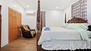 Une chambre à coucher avec un lit à baldaquin, une armoire en bois, un fauteuil en cuir et un rideau à motifs.