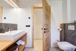 Un baño moderno con puerta de madera, un lavabo blanco y un inodoro.