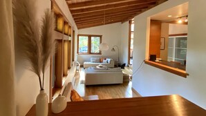 Een modern interieur met een houten plafond, een bank, een eettafel en een keukenhoek.