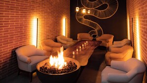 Ein gemütlicher Lounge-Bereich mit Backsteinwand, Feuerstelle und zwei Sesseln.