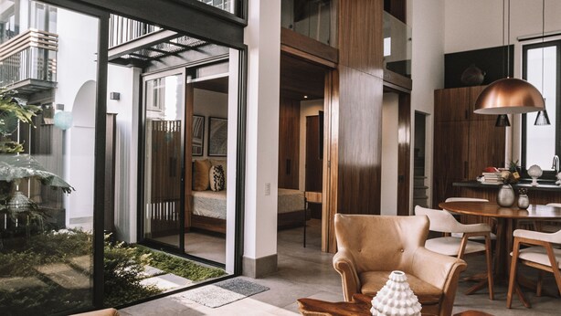 Ein modernes Interieur mit einer großen Glasdoor, die auf einen Balkon führt, einem Holztisch und einem Essbereich mit Stühlen.