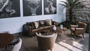 Ein modernes Wohnzimmer mit Steinwand, Holzboden und drei großen abstrakten Gemälden.