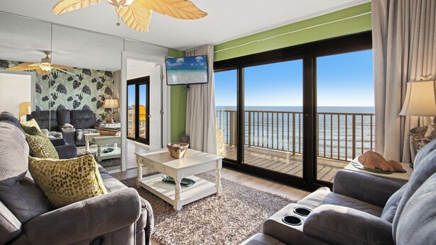 A modern living room with a large balcony, a ceiling fan, and a TV.