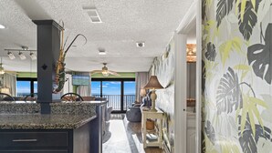 A modern kitchen with a granite countertop, a large island, and a view of the ocean.