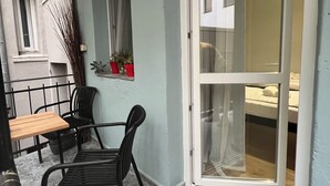 Ett litet, ombonat rum med en skjutdörr i glas som leder ut till en säng, ett litet bord med stolar och ett fönster med gardiner.