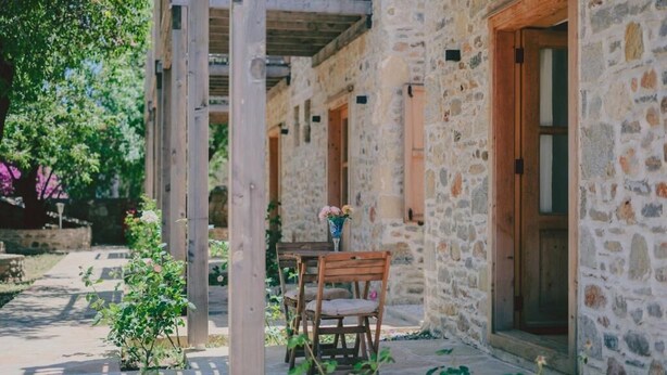 A stone building with a wooden door and a table with chairs outside. - Gulhiz (Datca)