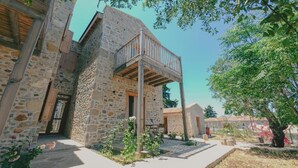 A stone building with a wooden balcony, surrounded by greenery and a clear sky. - Gulhiz (Datca)
