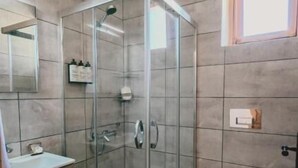 A modern bathroom with a glass-enclosed shower, a vanity with a mirror, and a toilet. - Gulhiz (Datca)