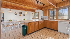 Una cocina con armarios de madera, encimera blanca y suelo de baldosas.