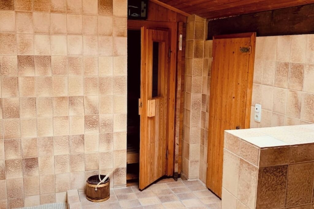 Une petite salle de bain aux murs carrelés, avec une porte en bois et un lavabo.