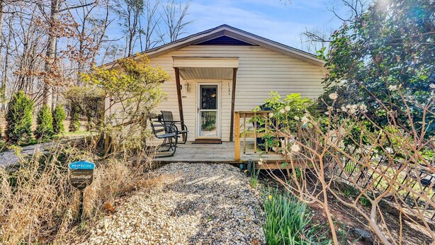 A single-story house with a porch, a chair, and a gravel path leading to the entrance.