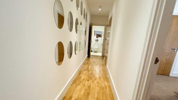 Ein Korridor mit Holzboden und mehreren runden Spiegeln an der Wand.