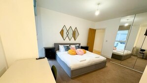 Ein Schlafzimmer mit Bett, Nachttisch, Stuhl, Schreibtisch und Spiegel.