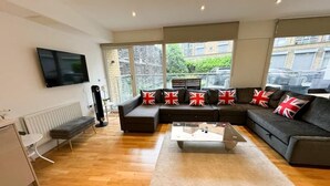 Ein modernes Wohnzimmer mit einer Eckcouch, einem Couchtisch und einem an der Wand befestigten Fernseher.